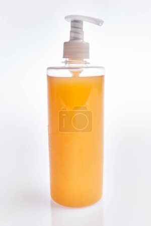 Photo for A translucent orange soap dispenser against a white background - Royalty Free Image