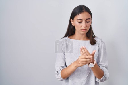 Téléchargez les photos : Jeune femme hispanique debout sur fond blanc souffrant de douleur aux mains et aux doigts, inflammation de l'arthrite - en image libre de droit
