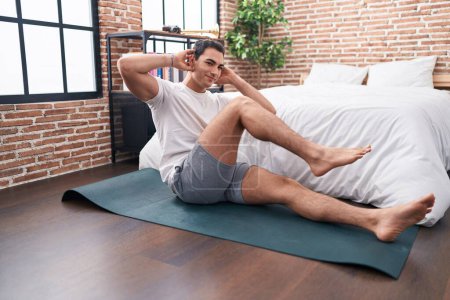 Photo for Young hispanic man smiling confident training abs exercise at bedroom - Royalty Free Image