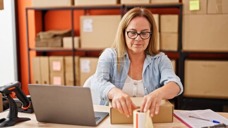 Photo for Middle age hispanic woman ecommerce business worker preparing package at office - Royalty Free Image