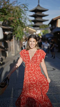 Téléchargez les photos : Tournant dans la joie, une belle femme hispanique dévoile sa robe dans les anciennes rues de la gion, kyoto, son sourire rayonnant ajoutant du charme à cette vieille ville japonaise hypnotisante. - en image libre de droit
