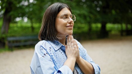 Foto de Joven mujer hispana hermosa rezando con los ojos cerrados en el parque de Viena - Imagen libre de derechos