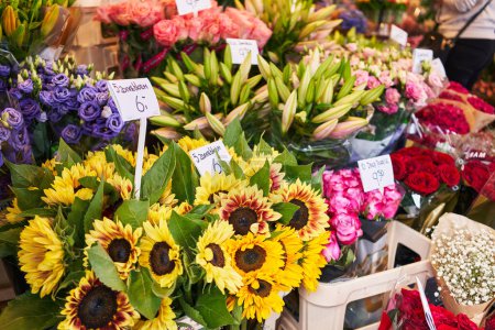 Foto de Colorido mercado de flores con ramos de girasoles, rosas y lirios, etiquetas que muestran los precios en euros. - Imagen libre de derechos