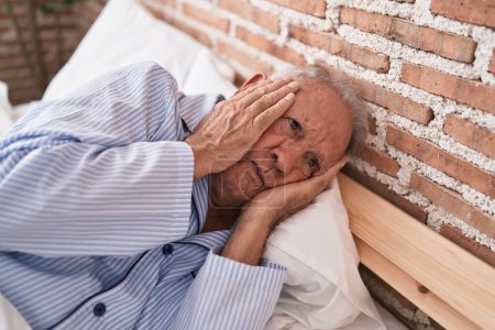 Téléchargez les photos : Moyen âge homme aux cheveux gris stressé couché sur le lit dans la chambre - en image libre de droit