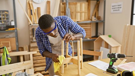 Foto de Carpintero afroamericano finamente arenosa una silla hecha a mano en un taller de carpintería bien equipado - Imagen libre de derechos