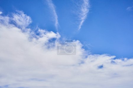 Téléchargez les photos : Un ciel bleu serein parsemé de nuages blancs et sanglants, transmettant un sentiment de tranquillité et d'espace. - en image libre de droit