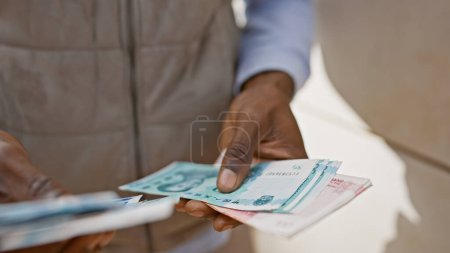 Téléchargez les photos : Homme africain compte monnaie yuan chinois à l'extérieur sur une rue de la ville. - en image libre de droit