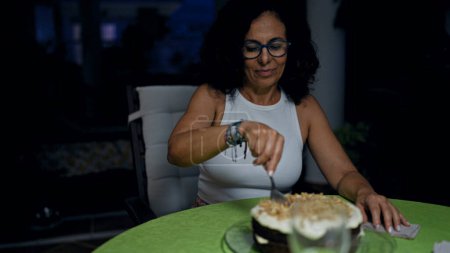 Foto de Mujer hispana madura disfrutando del postre en casa durante la noche - Imagen libre de derechos