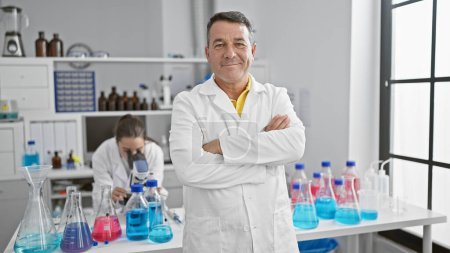 Photo for Confident male and female scientists joyfully working together, arms crossed in a gesture of camaraderie in their bustling laboratory - Royalty Free Image