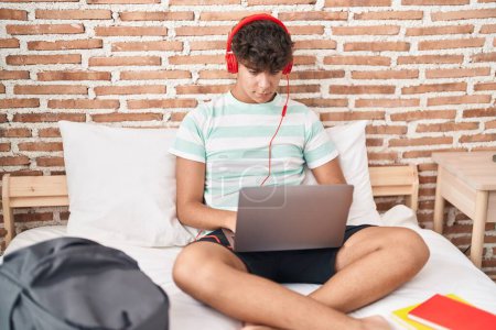 Photo for Young hispanic teenager student listening to music studying at bedroom - Royalty Free Image