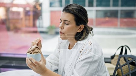 Photo for Beautiful young hispanic woman eating ice cream at cafeteria - Royalty Free Image