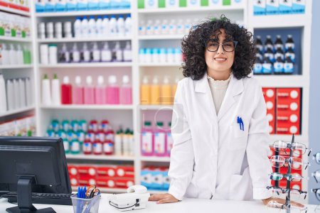 Photo for Young middle eastern woman pharmacist smiling confident standing at pharmacy - Royalty Free Image