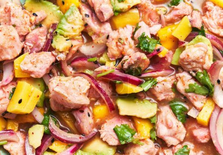 Photo for Close-up of a vibrant ceviche dish with salmon, avocado, mango, cilantro, and onions against a blurred background. - Royalty Free Image