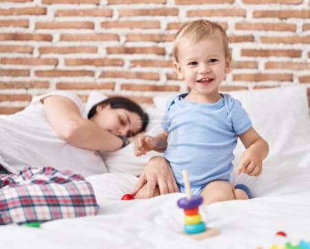 Téléchargez les photos : Mère et fils jouant sur le lit et dormant dans la chambre - en image libre de droit