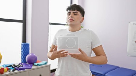 Photo for A young man focuses on breathing exercises indoors at a rehab clinic surrounded by therapy equipment. - Royalty Free Image