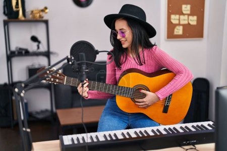 Photo for Young caucasian woman musician smiling confident playing classical guitar at music studio - Royalty Free Image
