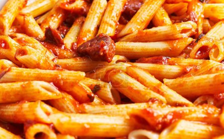Photo for Close-up of penne pasta in tomato sauce with herbs, perfect for italian cuisine culinary concepts. - Royalty Free Image