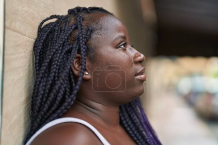 Téléchargez les photos : Femme afro-américaine regardant vers le côté avec une expression sérieuse dans la rue - en image libre de droit