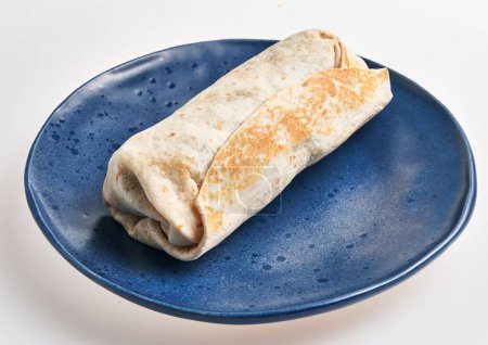 Foto de Un burrito fresco envuelto firmemente y servido en un plato de cerámica azul sobre un fondo blanco. - Imagen libre de derechos