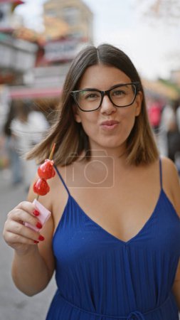 Photo for Stunning hispanic woman savors yummy japanese strawberry candy on nakamise street, an iconic tokyo spot - Royalty Free Image