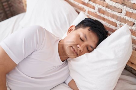 Photo for Young chinese man lying on bed sleeping at bedroom - Royalty Free Image