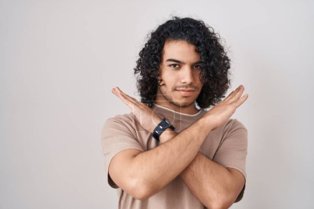 Téléchargez les photos : Homme hispanique aux cheveux bouclés debout sur fond blanc expression de rejet croisant les bras faisant signe négatif, visage en colère - en image libre de droit