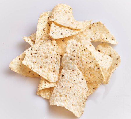 Foto de Primer plano de una pila fresca de chips de tortilla sobre un fondo blanco liso, ideal para temas de comida y meriendas. - Imagen libre de derechos