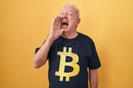 Téléchargez les photos : Homme âgé avec les cheveux gris portant Bitcoin t-shirt criant et criant fort à côté avec la main sur la bouche. concept de communication. - en image libre de droit