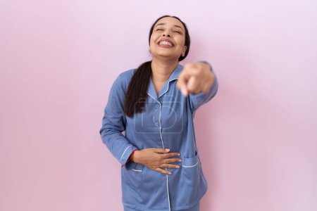 Téléchargez les photos : Jeune femme arabe en pyjama bleu se moquant de vous, pointant du doigt la caméra avec la main sur le corps, expression de honte - en image libre de droit