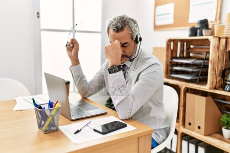 Téléchargez les photos : Moyen-âge homme aux cheveux gris agent du centre d'appels stressé de travailler au bureau - en image libre de droit