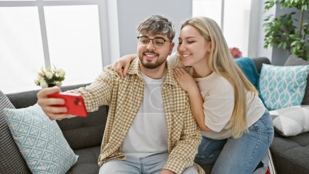 A loving couple takes a selfie in a cozy apartment living room, displaying affection and a modern interior.