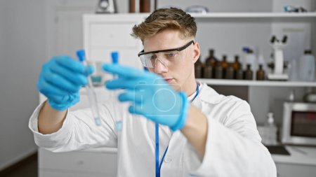 Foto de Hombre joven caucásico científico mirando tubos de ensayo en el laboratorio - Imagen libre de derechos