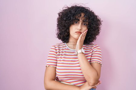 Photo for Young middle east woman standing over pink background thinking looking tired and bored with depression problems with crossed arms. - Royalty Free Image