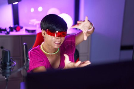 Téléchargez les photos : Middle age chinese woman streamer playing video game using virtual reality glasses at gaming room - en image libre de droit