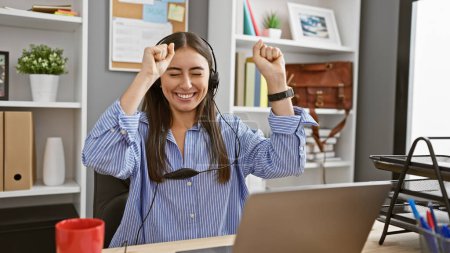 Téléchargez les photos : Une jeune femme hispanique joyeuse célébrant le succès dans un espace de travail de bureau moderne. - en image libre de droit