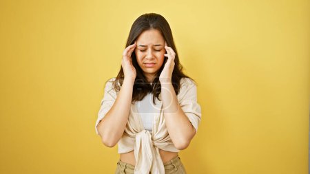Photo for Young beautiful hispanic woman suffering for headache over isolated yellow background - Royalty Free Image