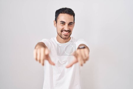 Photo for Handsome hispanic man standing over white background pointing to you and the camera with fingers, smiling positive and cheerful - Royalty Free Image
