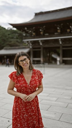 Photo for Cheerful beautiful hispanic woman with glasses posing confidently at traditional meiji temple, exuding success and joy in tokyo, japan - Royalty Free Image