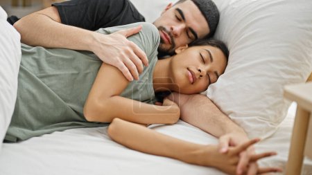 Foto de Hermosa pareja enamorada, acostados juntos en la cama, abrazándose mientras duermen en su acogedor dormitorio, disfrutando de la comodidad de la relajación y el descanso mientras expresan sus lazos familiares - Imagen libre de derechos