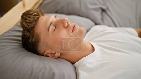 Téléchargez les photos : Jeune homme caucasien couché sur le lit dormant dans la chambre - en image libre de droit