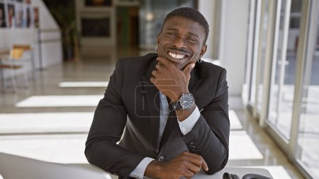Photo for A smiling african american man in a modern office setting exuding confidence and professionalism. - Royalty Free Image