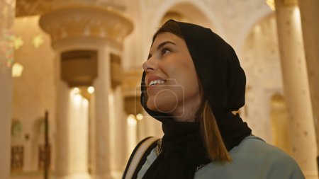 Téléchargez les photos : Femme souriante en hijab admirant l'architecture islamique dans une mosquée abu dhabi - en image libre de droit