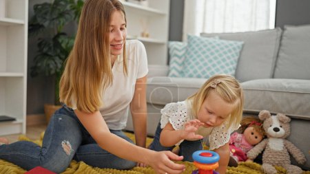 Photo for Relaxing at home, a caucasian mother and daughter, resting on the comfortable living room floor, share a joyful moment, playing a heartwarming hoop game together with big smiles. - Royalty Free Image