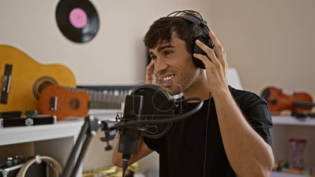 Téléchargez les photos : Homme confiant, jeune artiste hispanique chantant joyeusement son cœur dans un studio de musique, incarnant la mélodie de son âme - en image libre de droit