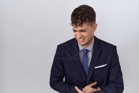 Téléchargez les photos : Jeune homme d'affaires hispanique portant costume et cravate avec la main sur le ventre parce que les nausées, la maladie douloureuse se sentent mal. concept de douleur. - en image libre de droit