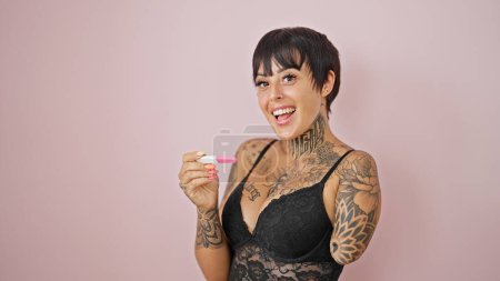 Téléchargez les photos : Femme hispanique avec le bras amputé portant lingerie regardant test de grossesse souriant sur fond rose isolé - en image libre de droit