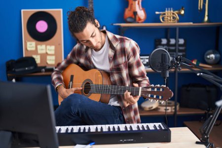 Téléchargez les photos : Jeune musicien hispanique jouant de la guitare classique au studio de musique - en image libre de droit