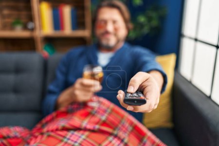 Photo for Middle age man wearing under eye patches watching television at home - Royalty Free Image