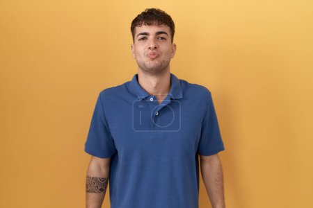 Photo for Young hispanic man standing over yellow background looking at the camera blowing a kiss on air being lovely and sexy. love expression. - Royalty Free Image