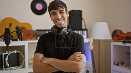 Téléchargez les photos : Jeune musicien hispanique souriant, portrait de confiance et de détente dans le studio de musique - en image libre de droit